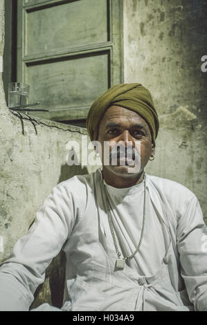 Regione GODWAR, India - 12 febbraio 2015: Indiano uomo vestito in abiti tradizionali si siede sul pavimento della cucina vicino alla finestra. Post-pr Foto Stock