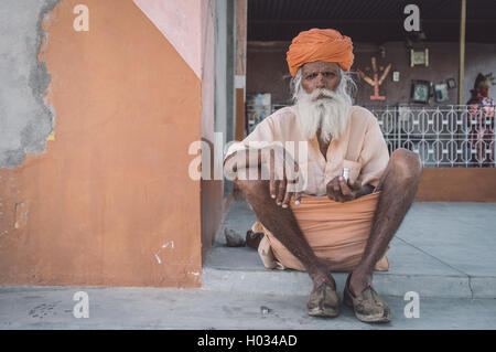 GODWAR, India - 12 febbraio 2015: Anziani tribesman indiano con turbante in lungi siede sul terreno nella parte anteriore del tempio. Post-proces Foto Stock