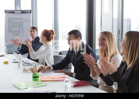 La gente di affari battendo le mani durante la riunione in ufficio moderno. Foto Stock
