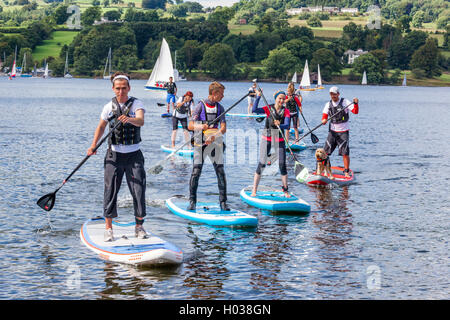 Giovani e un cane cercando la loro mano a paddle boarding durante un open day in Ullswater Yacht Club, Cumbria Regno Unito Foto Stock