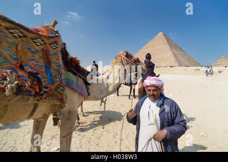 Il Cairo, Egitto - 3 febbraio 2016: uomo locale affitto cammello al turista di fronte alla grande Piramide di Giza. Foto Stock