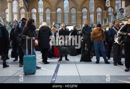 Pendolari / passeggeri cercando fino alla scheda di partenza, in attesa di treni in ritardo nella stazione di Liverpool Street, Londra Foto Stock