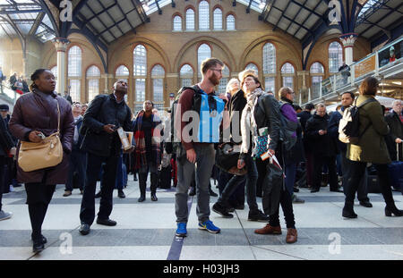 Pendolari / passeggeri cercando fino alla scheda di partenza, in attesa di treni in ritardo nella stazione di Liverpool Street, Londra Foto Stock