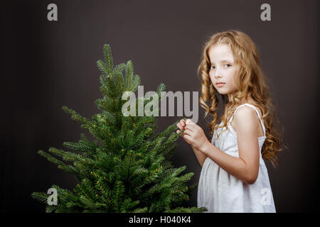 Poco brillante Pretty girl sorge nei pressi del concetto di albero Foto Stock