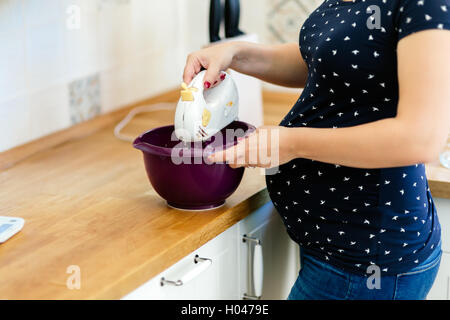 Donna incinta preparare i cookie in cucina Foto Stock