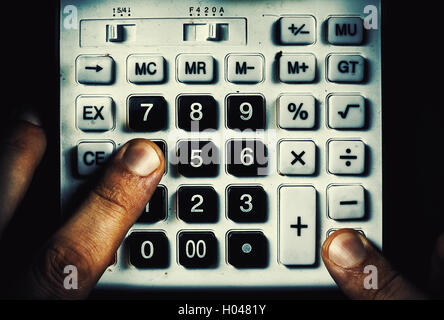 Composizione concettuale circa il calcolo, due dita su una vecchia calcolatrice polverosi pulsanti. Foto Stock