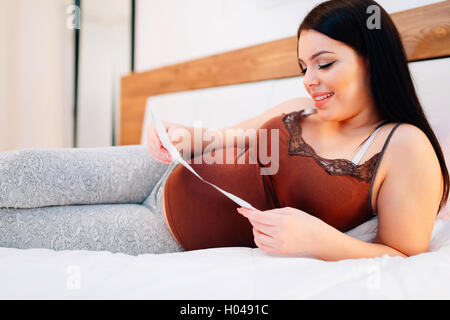 Donna incinta guardando la scansione del feto con la vera felicità Foto Stock