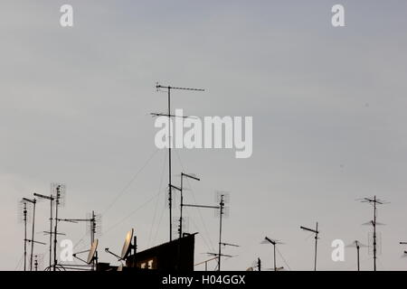 Antenne antenne televisive e parabole satellitari sul tetto con cielo blu chiaro Foto Stock