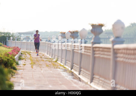 Donna sportiva jogging sul marciapiede alla mattina presto Foto Stock