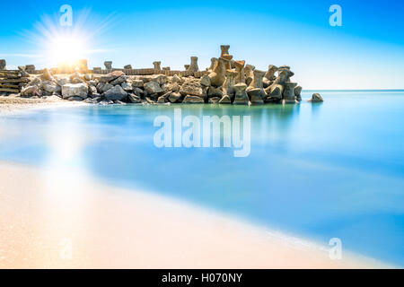 Esposizione lunga scena con Sunrise al di sopra di una spiaggia struttura frangiflutti, nella gura Portitei Black Sea resort, Romania Foto Stock