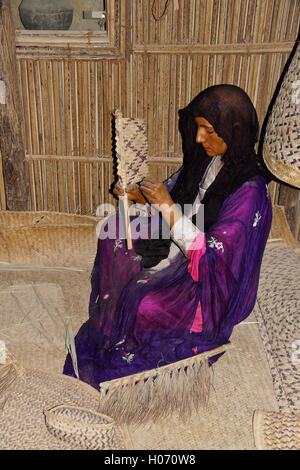 Donna tessitura di fronde di palma, presentano in Hatta Heritage Village, Dubai, Emirati Arabi Uniti Foto Stock