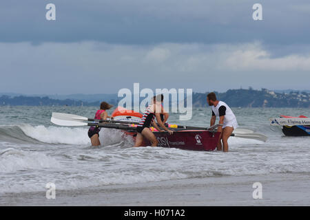 Barca a remi di essere lanciato dalla spiaggia sabbiosa attraverso oceanic onde da surf Foto Stock