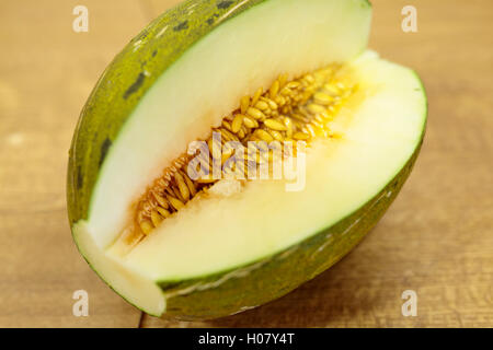 Pelle di rospo melone dimezzato su un tavolo di legno. Foto Stock