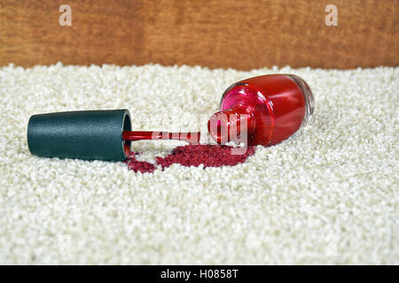 Rosso brillante smalto per unghie versato sul tappeto di colore chiaro Foto Stock