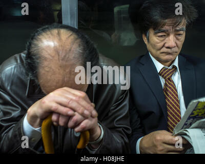 Stipendio stanchi uomini di dormire sul treno dei pendolari, Tokyo, Giappone Foto Stock