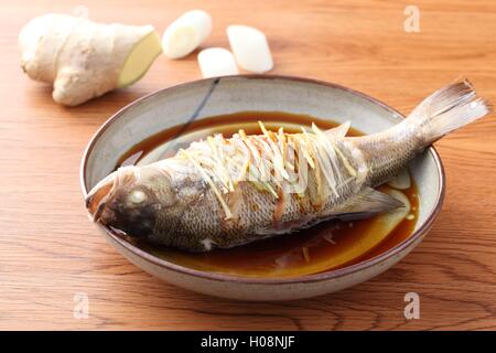 Cotto a vapore frittura di pesce intero in cinese tradizionale piastra con lo zenzero Foto Stock