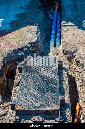 Cavi a fibra ottica sepolto in un micro trench con calcestruzzo colorato di rosso da un lavoratore Foto Stock