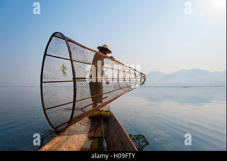 Un cestello pescatore sul Lago Inle si prepara a immergere il suo conformata a cono net, Stato Shan, Myanmar (Birmania), Asia Foto Stock