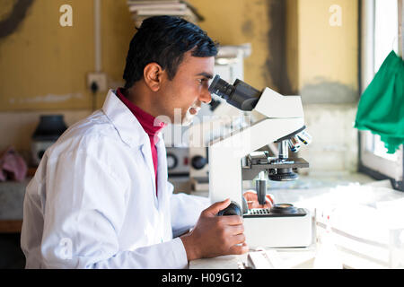 Un tecnico di laboratorio lavora in un laboratorio di un piccolo ospedale in Nepal guarda in un microscopio, Jiri, Solu Khumbu, in Nepal, in Asia Foto Stock