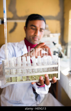 Un tecnico di laboratorio lavora in un laboratorio di un piccolo ospedale in Nepal detiene un rack di provette, Jiri, Solu Khumbu, in Nepal, in Asia Foto Stock