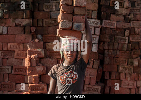 Un giovane uomo trasporta fino a 50 chili di mattoni da parte loro di bilanciamento sulla sua testa, fabbrica di mattoni nelle Chittagong Hill Tracts, Bangladesh Foto Stock