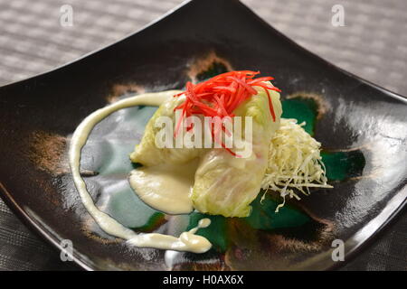 Involtini di cavolo con insalata mista sulla piastra nera Foto Stock