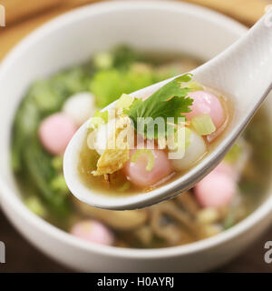 Zuppa speciale della palla di riso con le erbe sul cucchiaio bianco Foto Stock