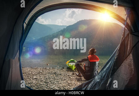 Attendamento e kayak sul lago. Sportivo caucasica Campeggio e kayak su Scenic Mountain Lake Shore. Foto Stock