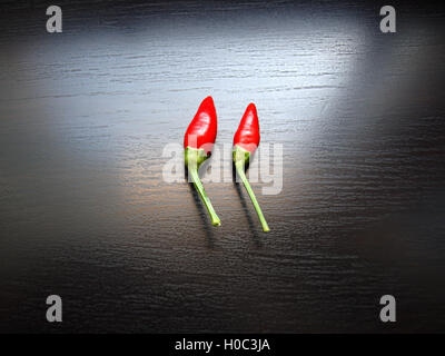 Due mature peperoncino rosso sulla superficie nera Foto Stock