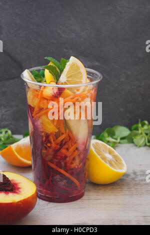 Insalata mista disposti in take away tazza di plastica trasparente con condimento al limone. Messa a fuoco selettiva, spazio di copia Foto Stock