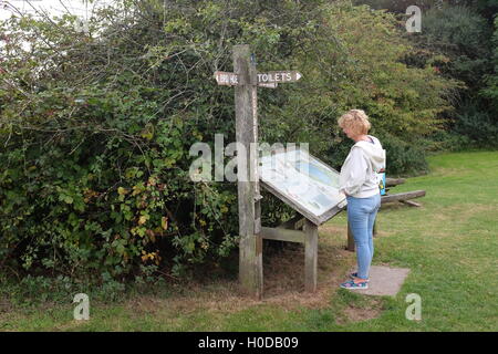 Donna walker la lettura di segnali di informazione a Arlington il serbatoio in East Sussex Regno Unito Foto Stock