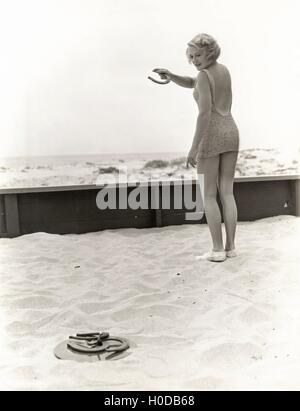 Vista posteriore della donna la riproduzione di cavalcate sulla spiaggia Foto Stock