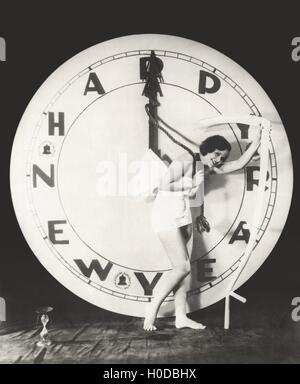 Donna tirando la lancetta delle ore del gigantesco orologio per la Vigilia di Capodanno Foto Stock