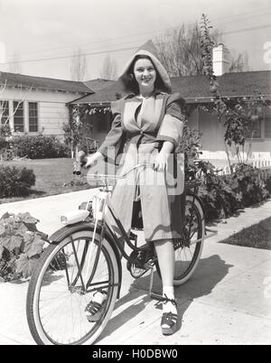 Donna in cappotto con cappuccio Bicicletta Equitazione Foto Stock