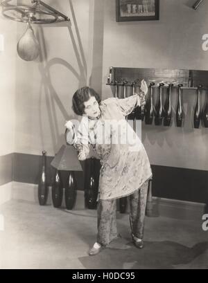 Determinata donna in seta pigiami sollevamento pesi nella palestra Foto Stock