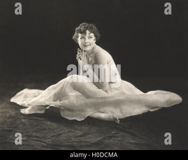 Donna sorridente in vestaglia seduto sul pavimento Foto Stock