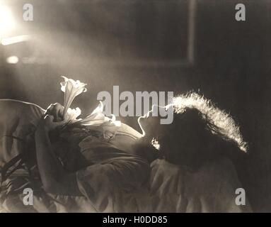 La luce del sole che cade su di donna con fiori dormire nel letto Foto Stock