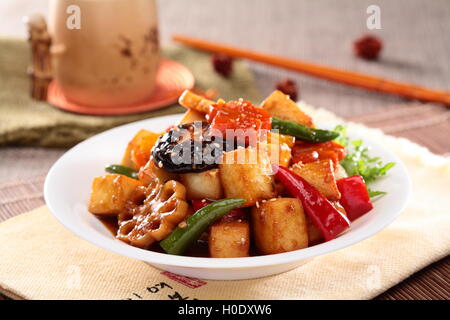Lotus root bollito lentamente il tofu con funghi, peperoncino e fette di lotus sulla piastra bianca Foto Stock