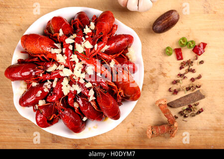 Red gamberi aglio sulla piastra bianca con spezie sul tavolo di legno Foto Stock