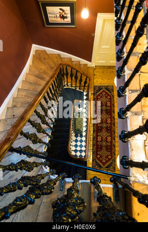 Una vertiginosa vista giù per le scale dal piano superiore di un alto vecchia casa. Foto Stock