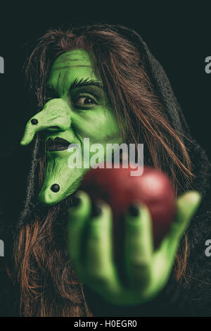 La strega verde tenendo un Apple nella sua mano. Profondità di campo. Foto Stock