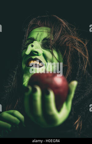 La strega verde ridere mentre si tiene un Apple nella sua mano. Profondità di campo. Foto Stock