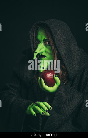 La strega verde in possesso di una mela marcia in una mano e un ragno in altri Foto Stock