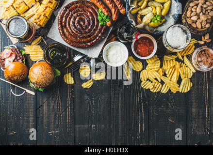 Birra e snack set. Oktoberfest cibo concetto di frame. Vatiety di birre, salsicce alla griglia, hamburger, mais, patate fritte, patatine, sa Foto Stock