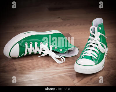 Retrò sneakers verde a sinistra sul pavimento in legno grungy effetti Foto Stock