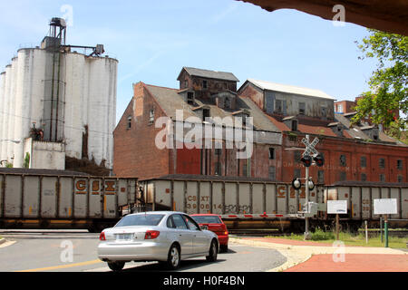 Lynchburg, Virginia, Stati Uniti. Il treno cargo passa accanto al Piedmont Flour Mill abbandonato e gli edifici di Silo su Jefferson Street. Foto Stock