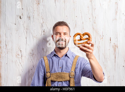 Uomo in tradizionali abiti bavarese holding pretzel Foto Stock