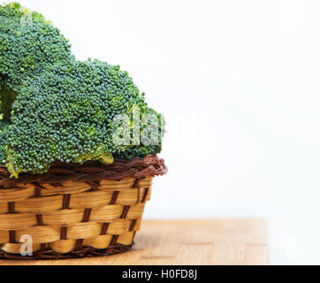Close up sui broccoli freschi solated nel cesto su legno e sfondo bianco Foto Stock