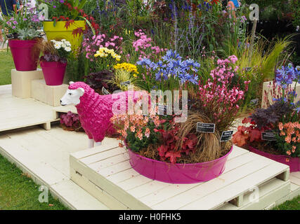 La visualizzazione di vari fiori che crescono in rosa dei vasi con una rosa di ovini in fibra di vetro a Tatton Park Flower Show 2016 nel Cheshire, UK. Foto Stock