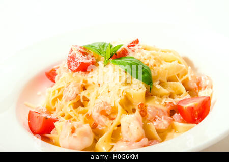 Fettuccine con gamberetti, i pomodori e la pasta a base di noodle sulla piastra bianca sullo sfondo Foto Stock